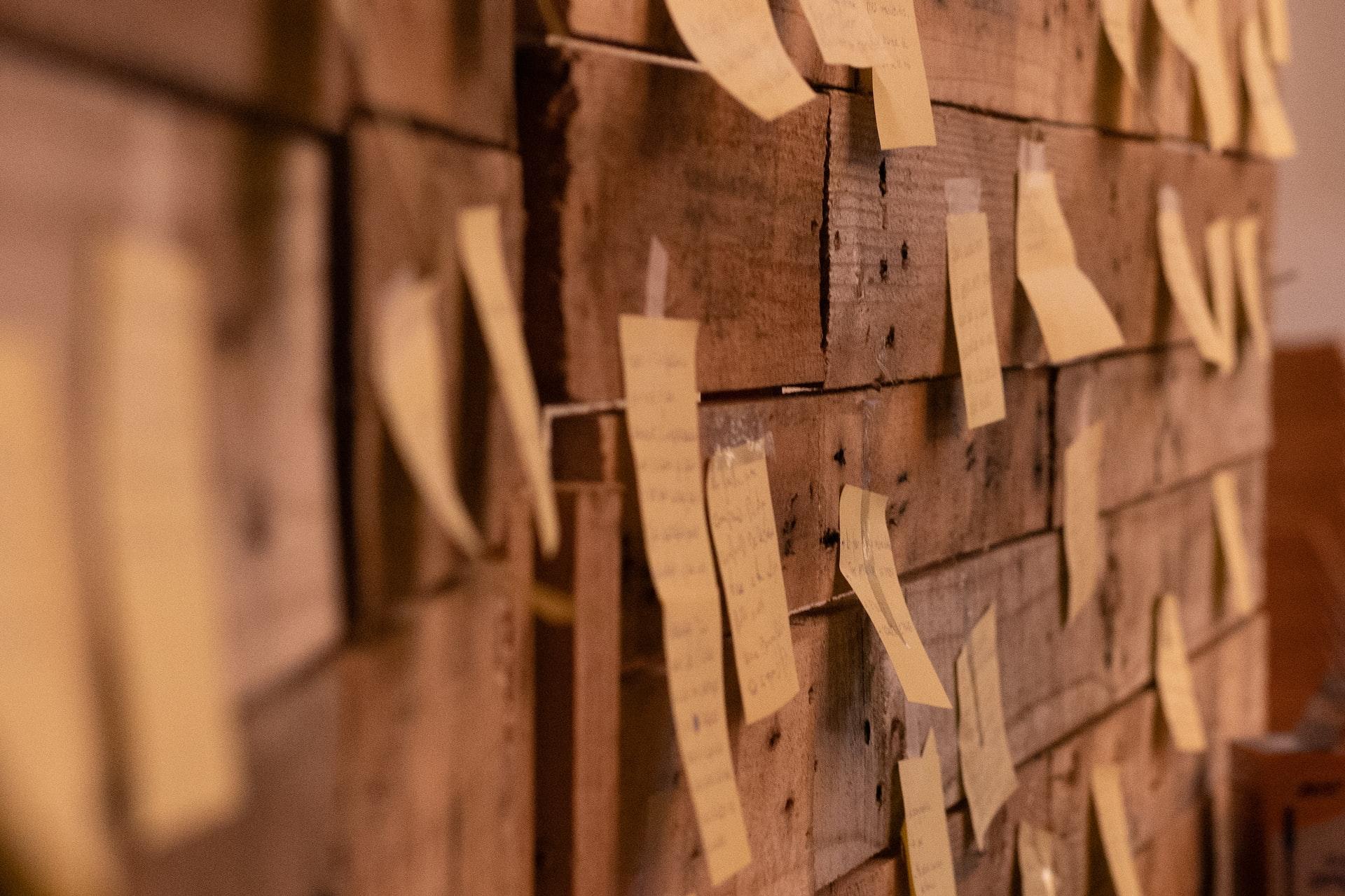 a wooden wall with post it notes attached to it